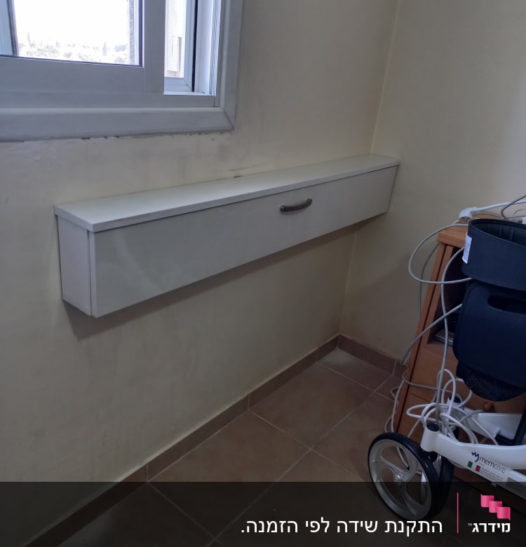 ארון עץ לבן עם ידית מתכת מתחת לחלון